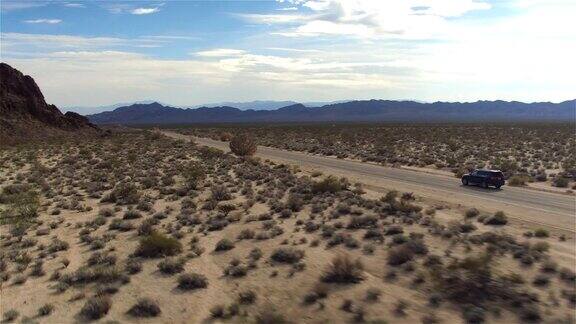 图片:一辆黑色SUV沿着空旷的乡村公路穿过沙漠