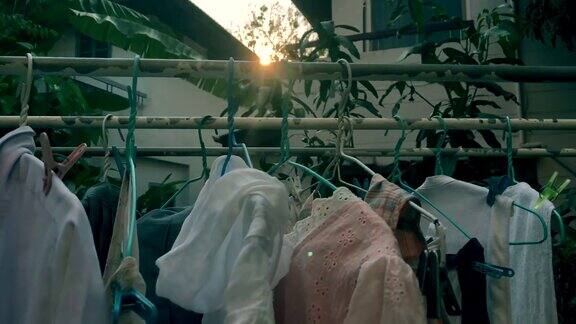 人的手把衣服晾在衣架上周围有太阳耀斑、鸟鸣的景象