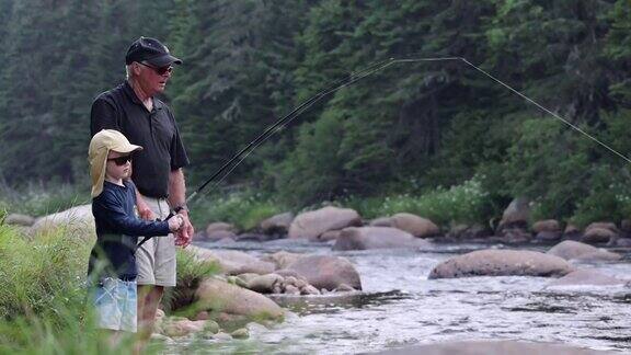 可爱的红发男孩和爷爷在魁北克的河里钓鱼
