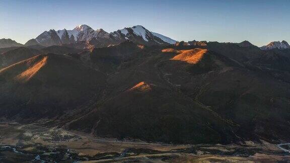 日出的光芒照亮了雪山的山顶