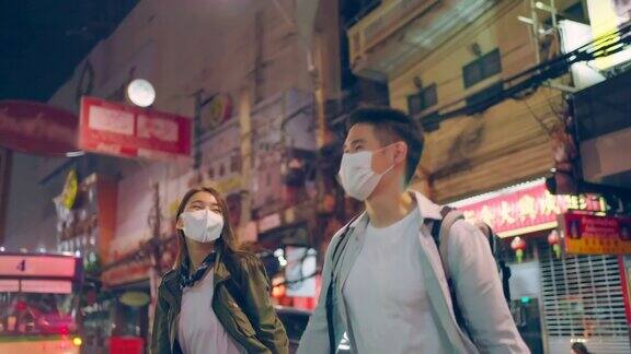 亚洲情侣戴着浪漫的面具在城市旅行度蜜月新婚男女背包客看手机寻找目的地在疫情期间一起享受假期