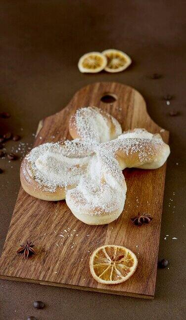 甜螺旋圆面包与椰子片和香草奶油在木板上棕色背景的烘焙糕点