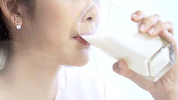 一位亚洲妇女正在喝一杯牛奶