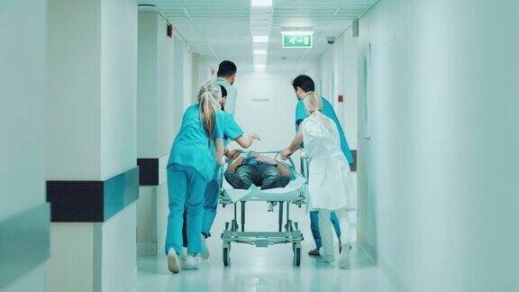 急诊科:医生护士和护理人员推动轮床担架与严重受伤的病人走向手术室明亮的现代医院专业人员挽救生命