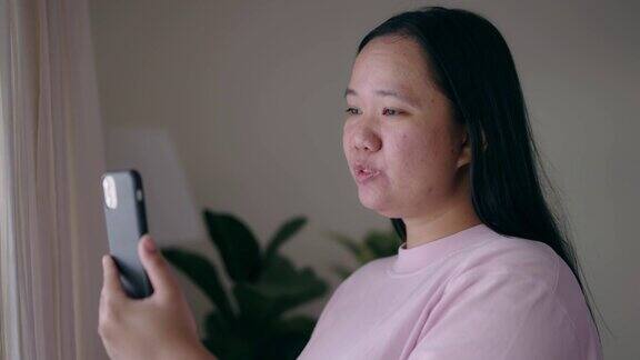 亚洲妇女用手机进行视频通话与她的微笑