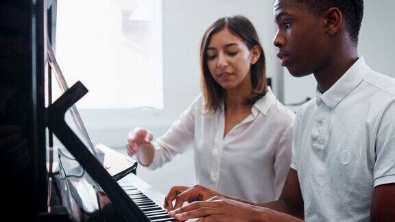 在音乐课上男学生和老师一起弹钢琴