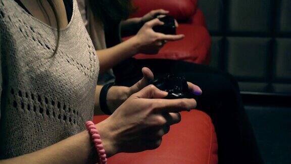 两个小女孩在红色沙发上用游戏手柄玩电子游戏