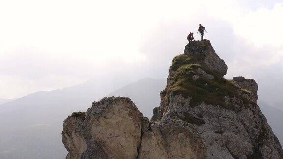 登山运动员攀登岩石的顶峰在深谷之上