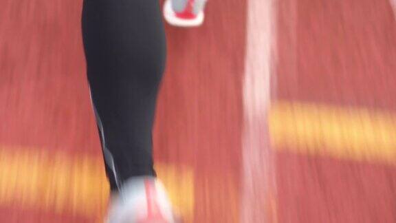 运动员在田径训练中穿着运动紧身衣在跑道上跑步的后视图