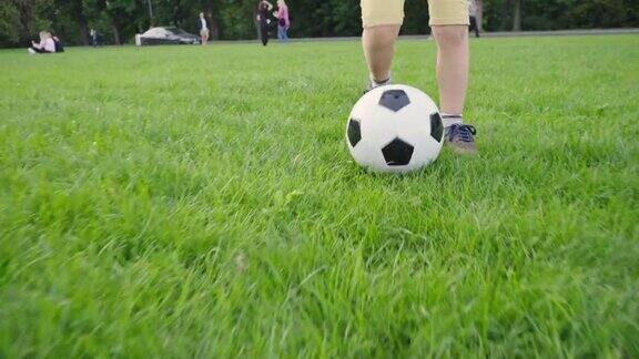 男孩在踢足球带着球的孩子跑过绿色的草地