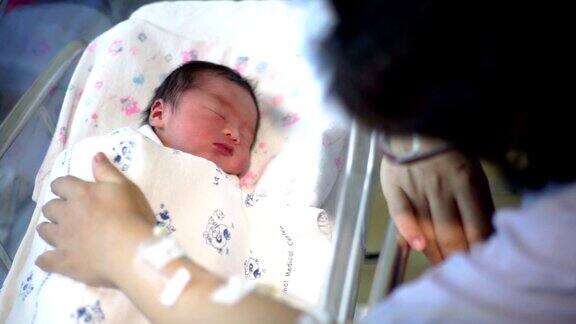 MS手持相机:一位母亲和她刚出生的婴儿在医院的婴儿床上睡觉
