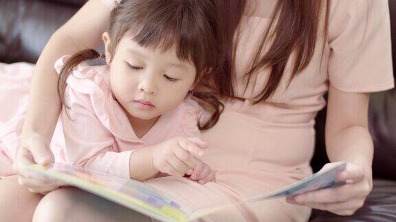 可爱的亚洲小女孩和她的妈妈在家里看书