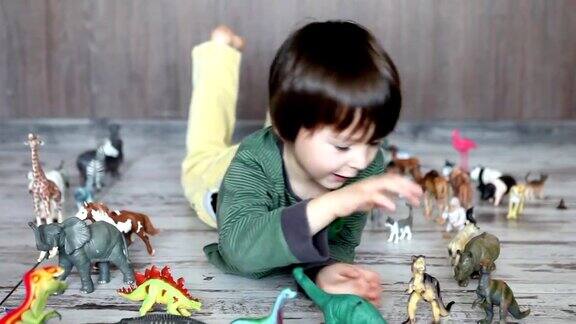 可爱的小男孩在地板上玩塑料动物和恐龙
