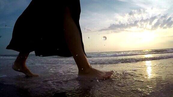 一个女人在沙滩上的海浪边行走的慢镜头