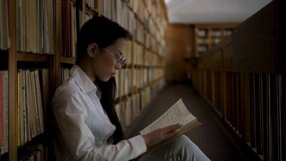年轻女子坐在大学图书馆的地板上看书