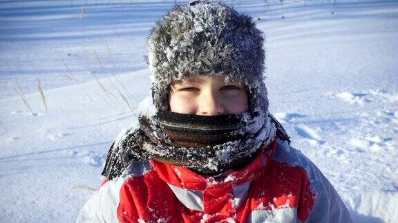 在冬季公园的雪地上快乐的男孩的肖像