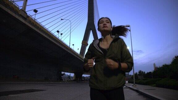 亚洲妇女早上在城市的吊桥步行道上跑步
