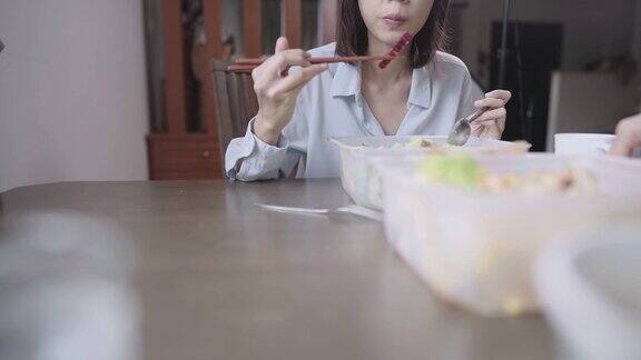 亚洲女性在家里餐桌上用餐使用筷子和勺子亚洲食品外卖服务应用蔬菜沙拉饮食营养外卖食品新常态待在家里锁定
