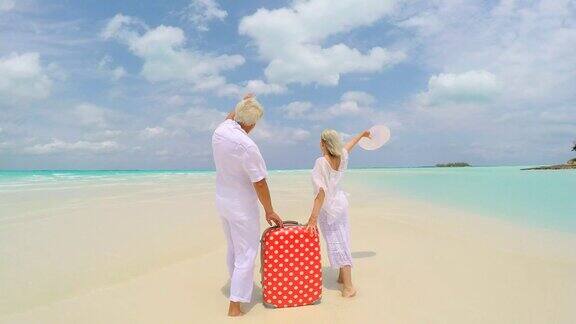 带着行李箱在海滩度假的白人退休老人