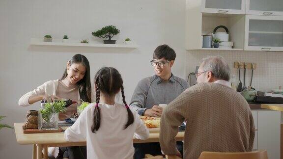 远景:快乐的亚洲家庭一起享用早餐快乐的父母爷爷和可爱的女儿在家里的餐桌上一起享用早餐美妙的时刻家庭