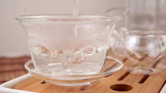 在杯子里泡茶将沸水从水壶倒入玻璃杯的过程