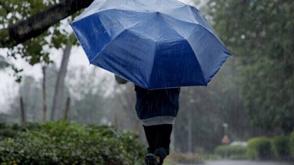 一个小男孩拿着伞在倾盆大雨中跳跃的慢动作