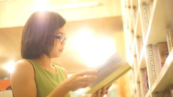 亚洲妇女在书店看书对书架的背景