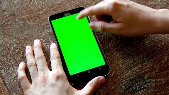 手用带有绿色屏幕的手机放在木桌上