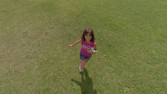 小女孩在绿地上追逐无人机摄像头