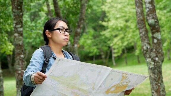 一名背着背包的女游客在森林里放松在地图上寻找正确的方向旅游和度假的生活方式