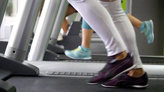 女性在健身房跑步机上行走和跑步年轻女性在有氧运动中锻炼女孩们穿着运动鞋在运动俱乐部室内训练慢跑的人近距离