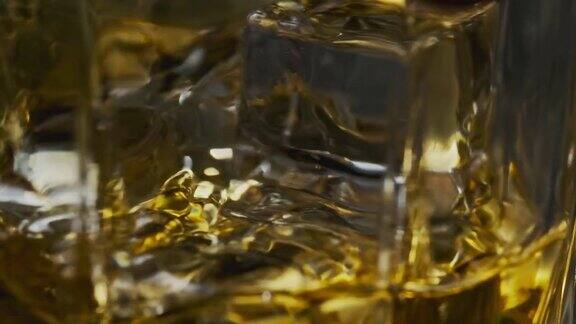 金色威士忌杯中冰块旋转微距慢动作拍摄