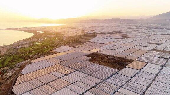 日落在世界上最大的温室集中与山的背景西班牙这是集约化生产环境问题-无人机鸟瞰图-农业和环境概念4K