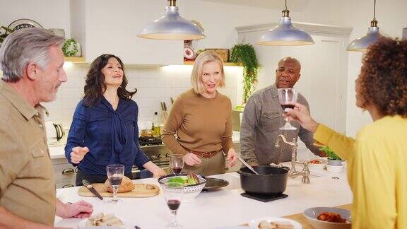 一群成熟的朋友在家里互相敬酒一起在厨房上菜用慢镜头拍摄