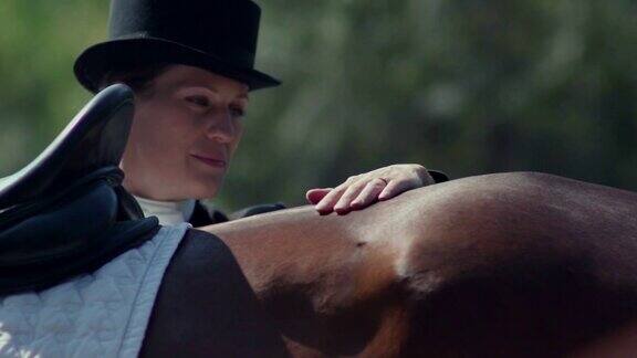 威瑟斯马一个穿着长礼服、戴着帽子的女骑手在抚摸着马