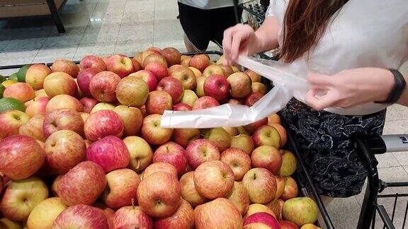 在超级市场买东西的女人在挑选苹果