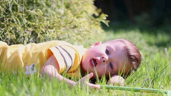 白种人小孩小孩男孩黄色衬衫躺在草地阳光明媚的日子里思考着做梦