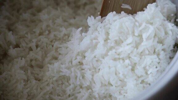 在电饭锅里煮米饭的特写镜头厨师用木铲从电饭锅里取出米饭