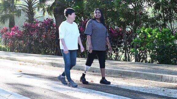 一名亚裔印度残疾人与假腿运动妇女慢跑在公共公园上午会议与一名活跃的中国老年妇女