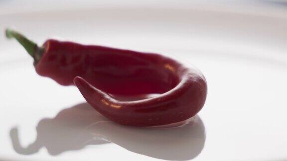 一个新鲜的红辣椒在白色盘子旋转特写