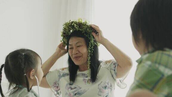 泰国祖母戴着皇冠叶在她的孙女和孙子旁边积极的情绪