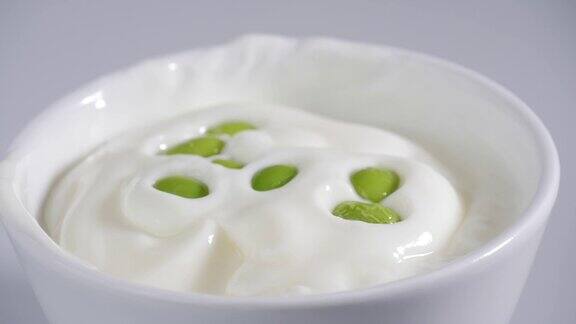 绿色的大豆落在酸奶碗上慢镜头