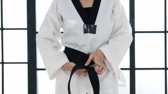 近距离拍摄的跆拳道女孩皮带黑带到她的衣服在白色的房间腰带上的文字是跆拳道的意思