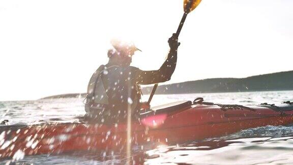 SLOMOTS男子在阳光下在海上乘坐皮划艇