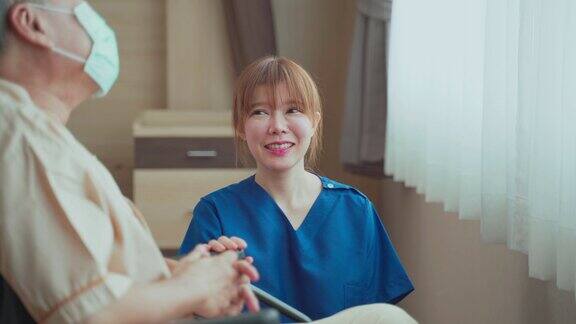 在医院照顾坐在轮椅上的成熟男性病人的亚洲护士年轻妇女和老人戴上外科口罩以预防covid-19大流行女孩对老人微笑