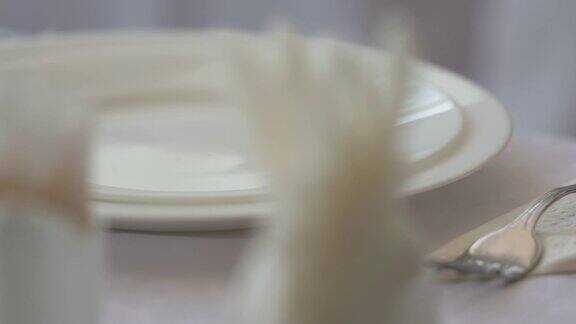精致的餐桌设置在餐厅的盘子刀叉和高脚餐具