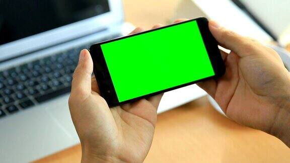 人类的手使用绿色屏幕的手机