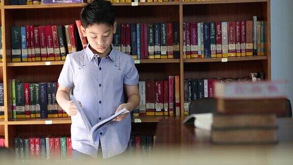 一个亚洲小男孩厌倦了阅读在泰国的图书馆