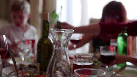 客人们举杯庆祝节日一群朋友在餐桌上喝含酒精的饮料眼镜的特写镜头