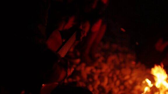 年轻人晚上围着营火弹吉他